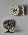 A pair of round organic cufflinks in silver, shown from both the front  and back (revealing a textured silver backing) on a neutral gray background.