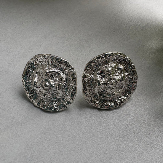 Two silver organic earrings  on a gray background