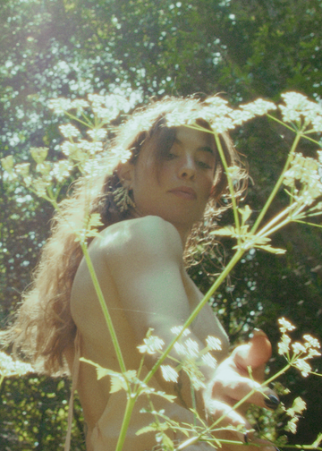 Woman standing among white flowers with a blurred green background