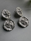 Round and textured pendal silver organic earrings on  a grey surface