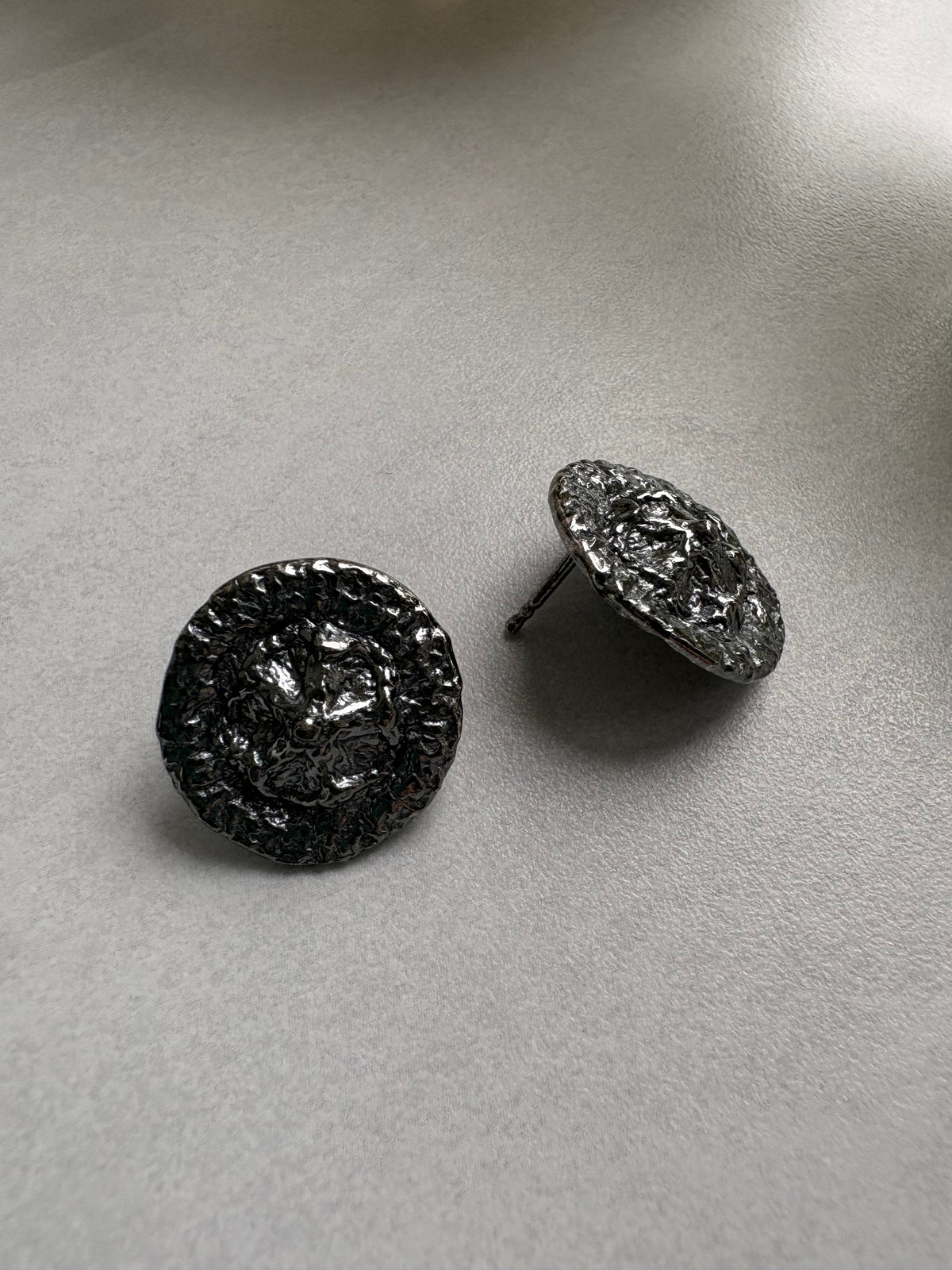 Pair of black rhodium-plated earrings on a light gray surface