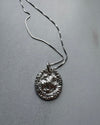 Silver necklace with a textured pendant on a gray surface