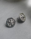 Pair of silver stud earrings on a gray surface