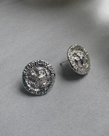 Pair of silver stud earrings on a gray surface