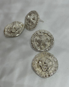 Two round and heavily textured silver earrings on a white  background, and one round stud showing the post back.