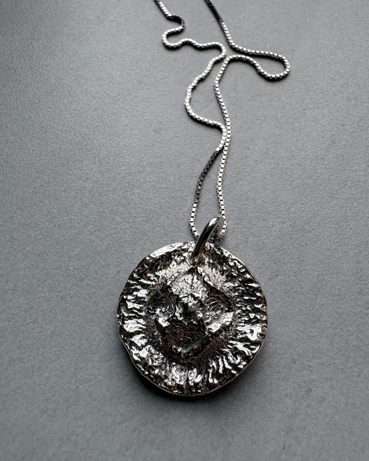 Organic Silver pendant necklace on a gray background