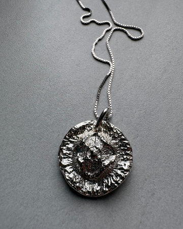 Organic Silver pendant necklace on a gray background