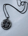 Silver necklace with a detailed pendant on a light gray background