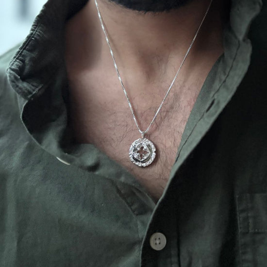 Man wearing a green shirt with a necklace featuring a circular pendant.