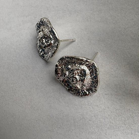 Pair of silver textured earrings on a light gray background