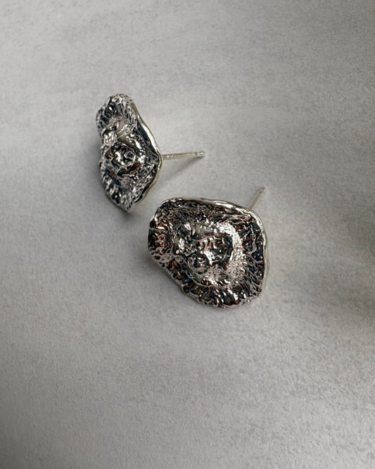 Pair of silver textured earrings on a light gray background