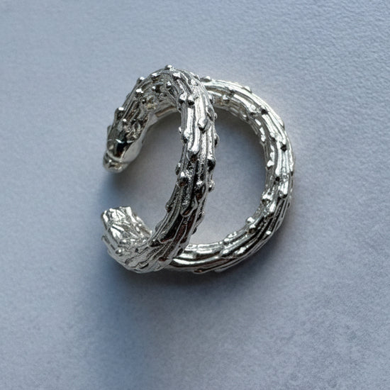 Silver ear cuff earring on a light blue background