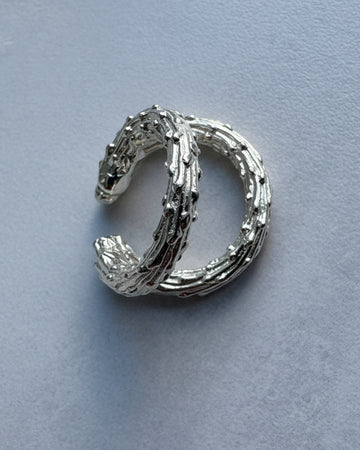 Silver ear cuff earring on a light blue background