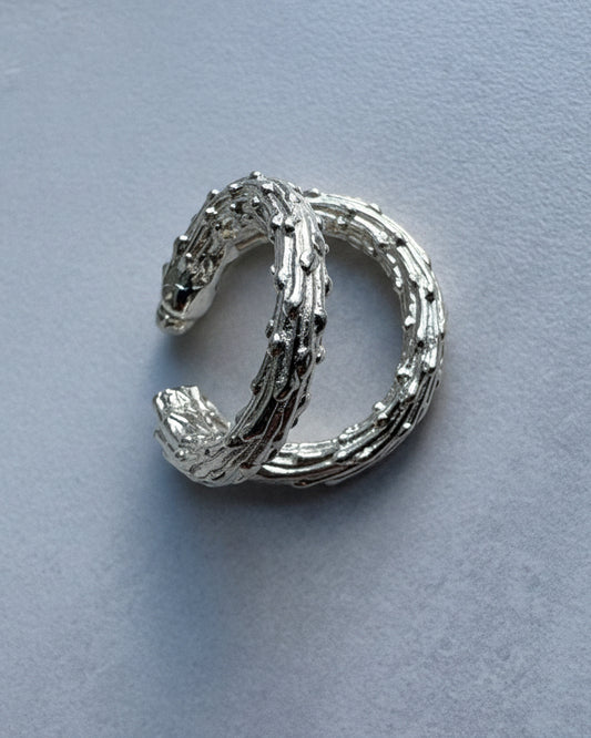 Silver ear cuff earring on a light blue background