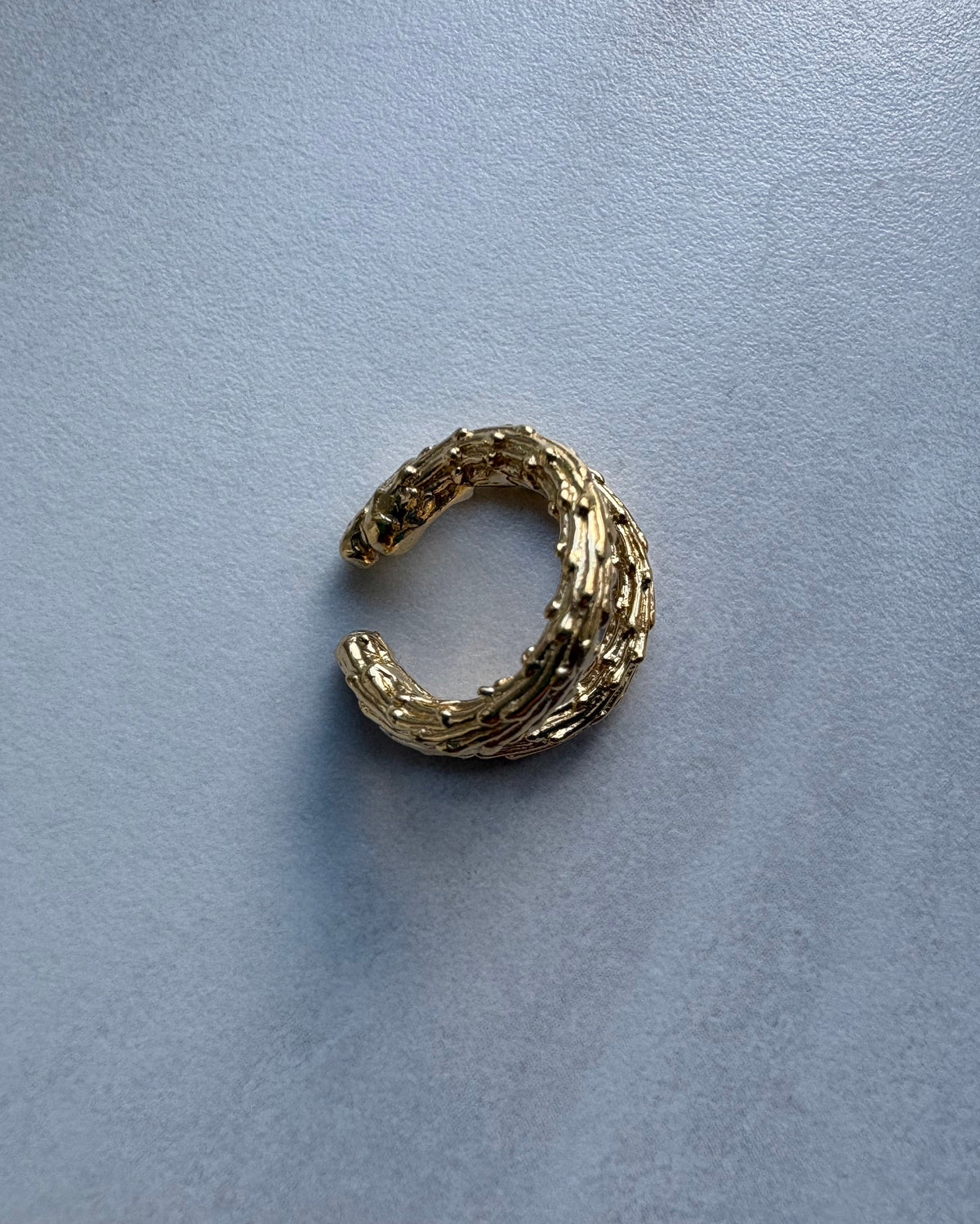 Gold organic ear cuff earring on a gray background