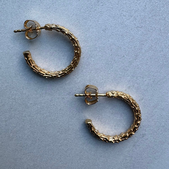 Gold hoop earrings on a light blue background