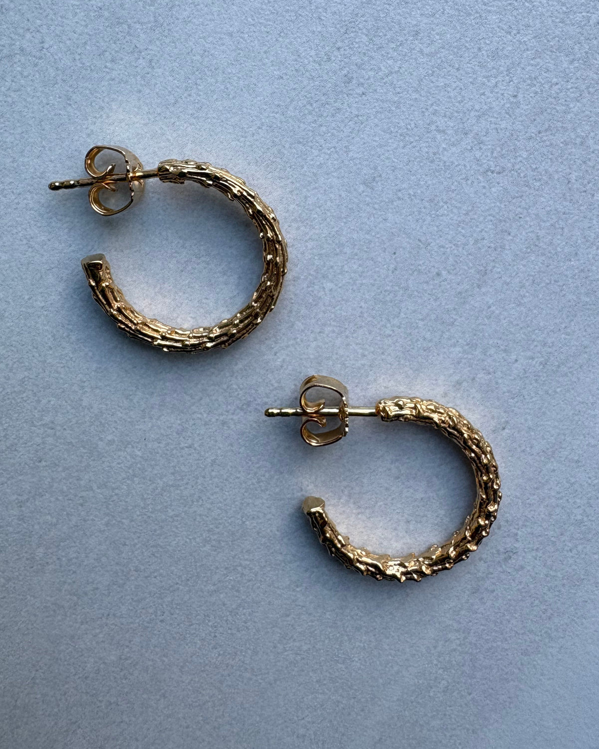 Gold hoop earrings on a light blue background