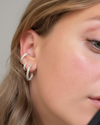 Close-up of a woman wearing silver hoop earrings with a neutral background