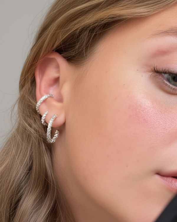 Close-up of a woman wearing silver hoop earrings with a neutral background