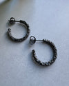 Pair of oxidised silver hoop earrings on a light gray surface
