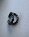 Black oxidised silver organic ear cuff  on a light gray background
