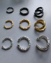 Set of gold, silver, and black hoop earrcuffs on a gray background