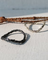 two organic silver rings one with black oxidation and branches of pine tree in the background