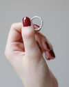 hand holding an organi silver ring on a grey background