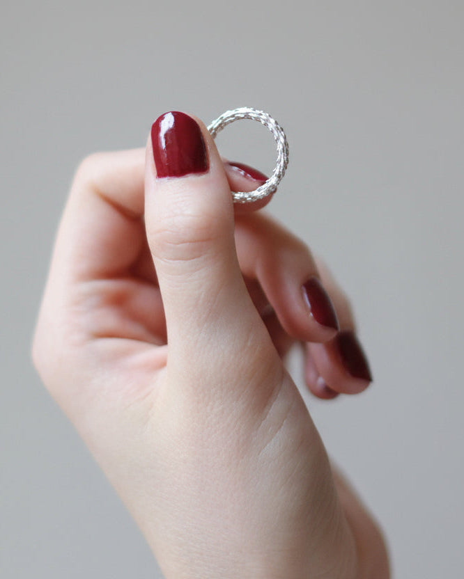 hand holding an organi silver ring on a grey background