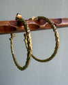 wooden stick holding two organic hoops earrings gold color