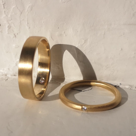 Two gold rings on a textured surface with a light gray background