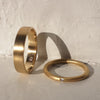 Two gold rings on a textured surface with a light gray background