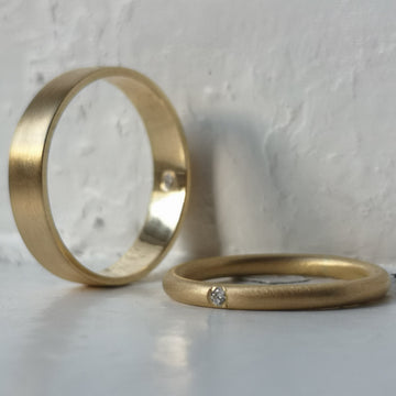 Two gold rings on a light gray surface
