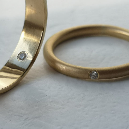 Two gold rings with embedded stones on a light background