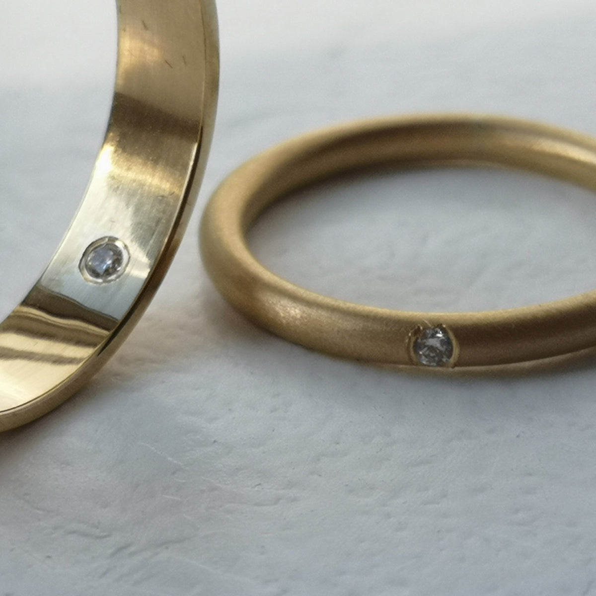 Two gold rings with embedded stones on a light background