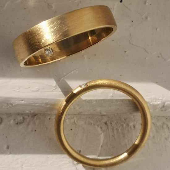 Two gold rings on a textured surface