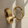 Two gold rings with small diamonds on a textured white surface