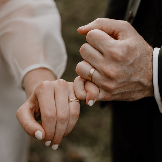Two people holding hands with a blurred natural background