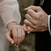 Two people holding hands with a blurred natural background
