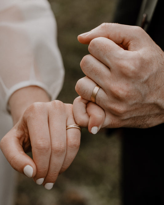 Two people holding hands with a blurred natural background