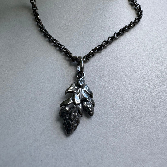 O xidised Silver necklace with a leaf pendant on a gray background