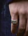 hand close up wearing a silver signet ring with a textured top part