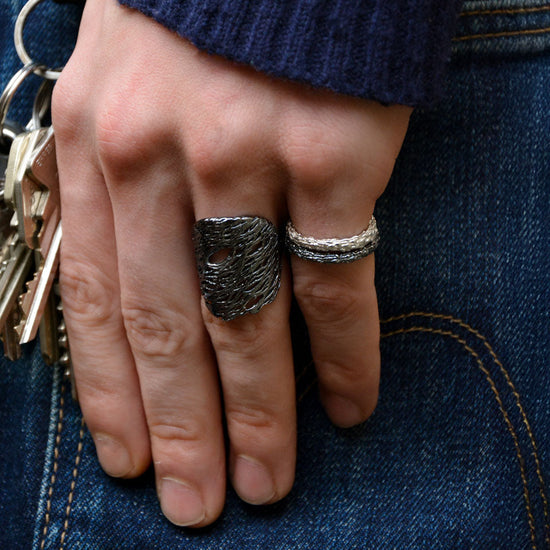 Hand wearing two rings holding keys against a denim background