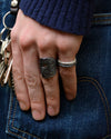 Hand wearing two rings holding keys against a denim background