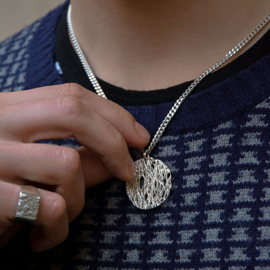 model with a textured blue and grey sweather wearing an organic botanical silver necklace and ring