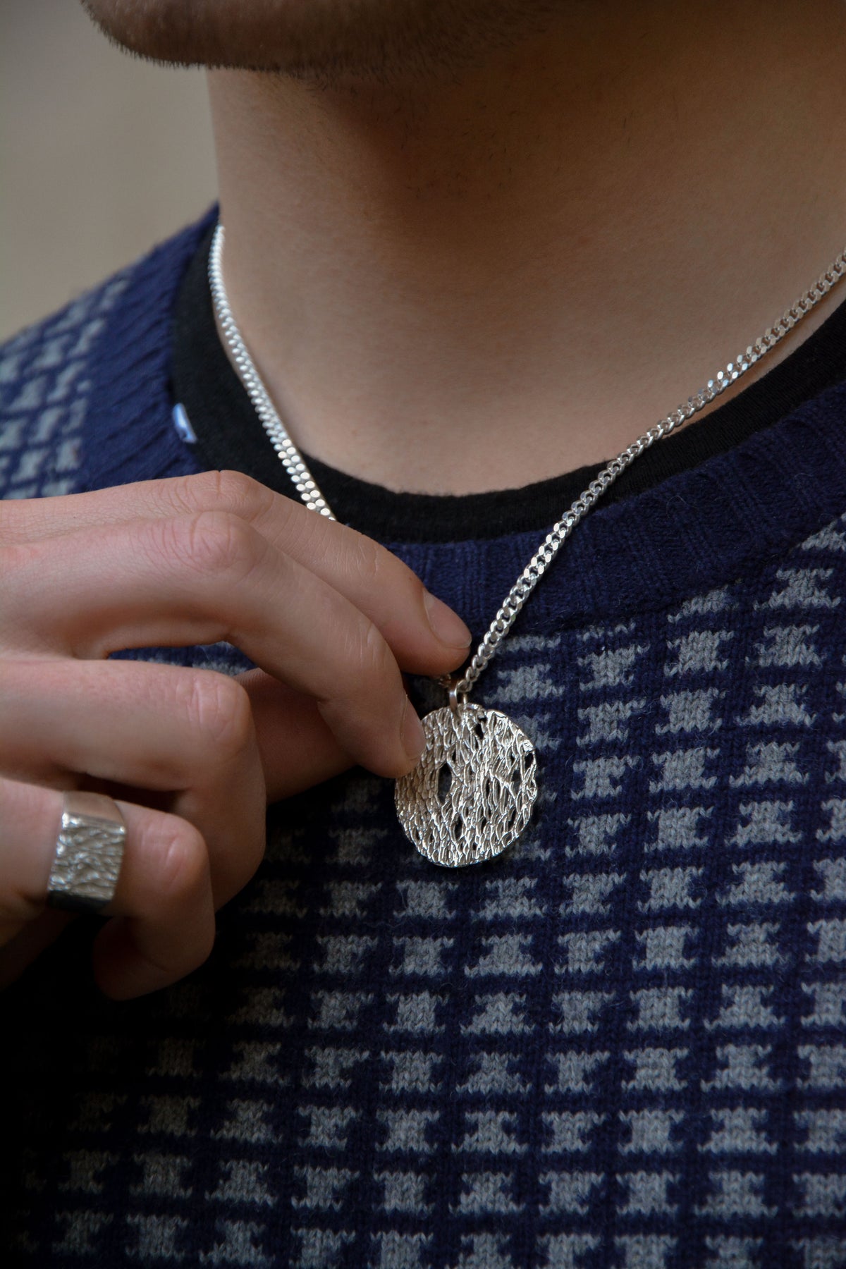 model with a textured blue and grey sweather wearing an organic botanical silver necklace and ring