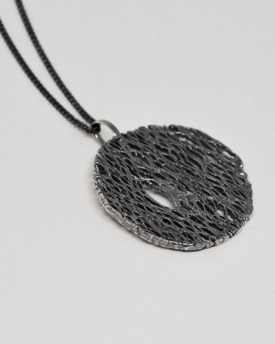 Black textured pendant necklace on a light gray background