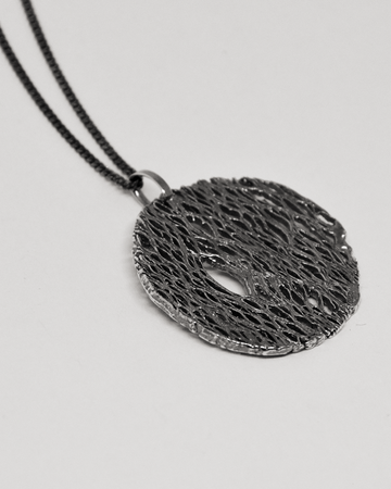 Black textured pendant necklace on a light gray background