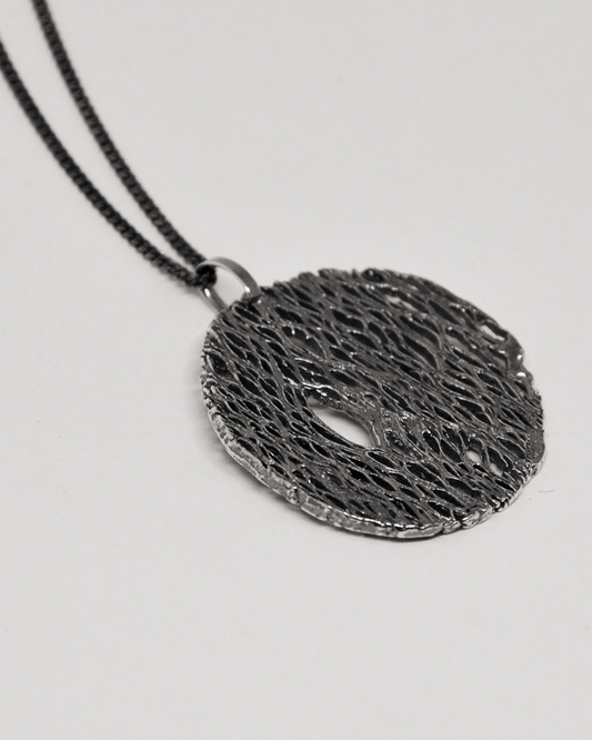 Black textured pendant necklace on a light gray background