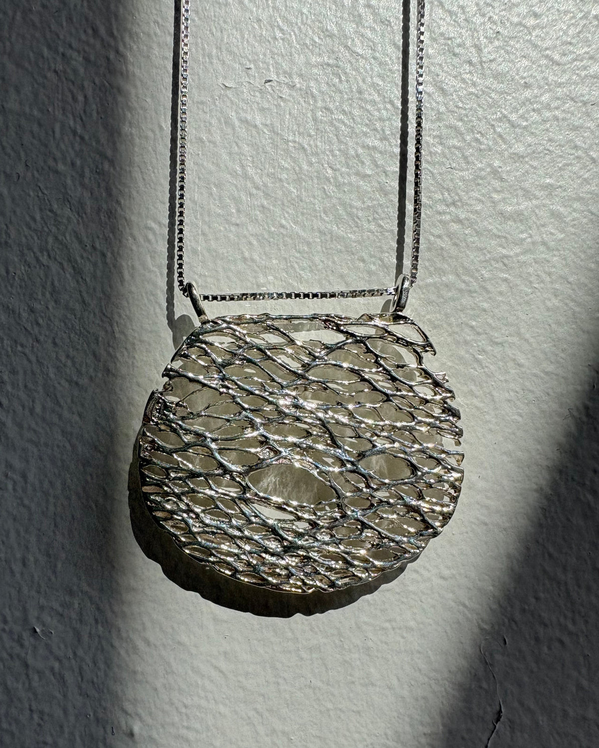 Close-up of a textured silver necklace on a plain background